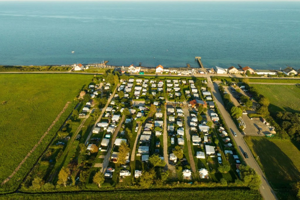 Luftaufnahme des Campingplatzes Auszeit 27 in Süssau-Strand mit Tiny Houses und Ostsee im Hintergrund