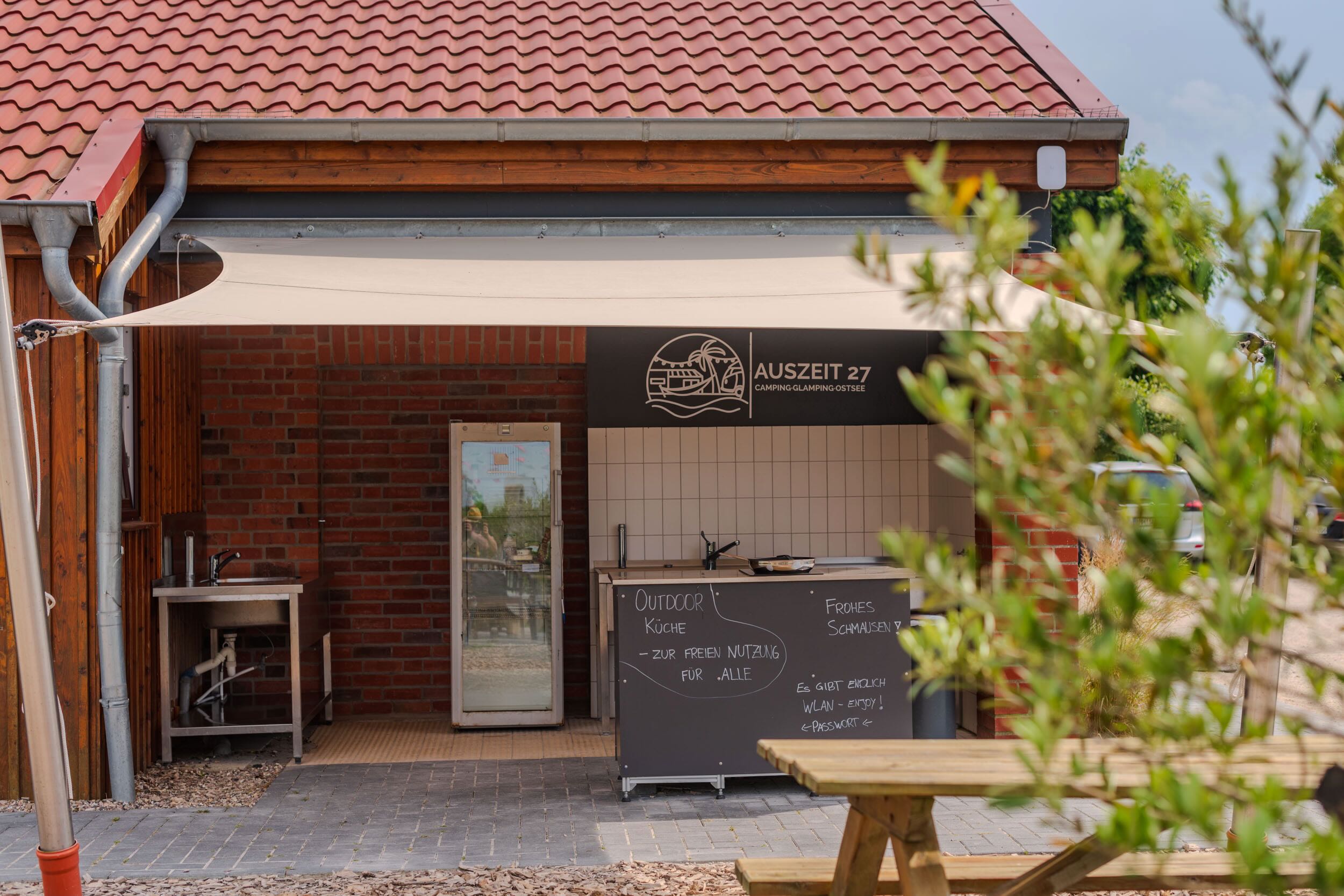 Gemeinschaftliche Outdoorküche mit Sonnensegel auf dem Campingplatz Auszeit 27 in Süssau-Strand an der Ostsee